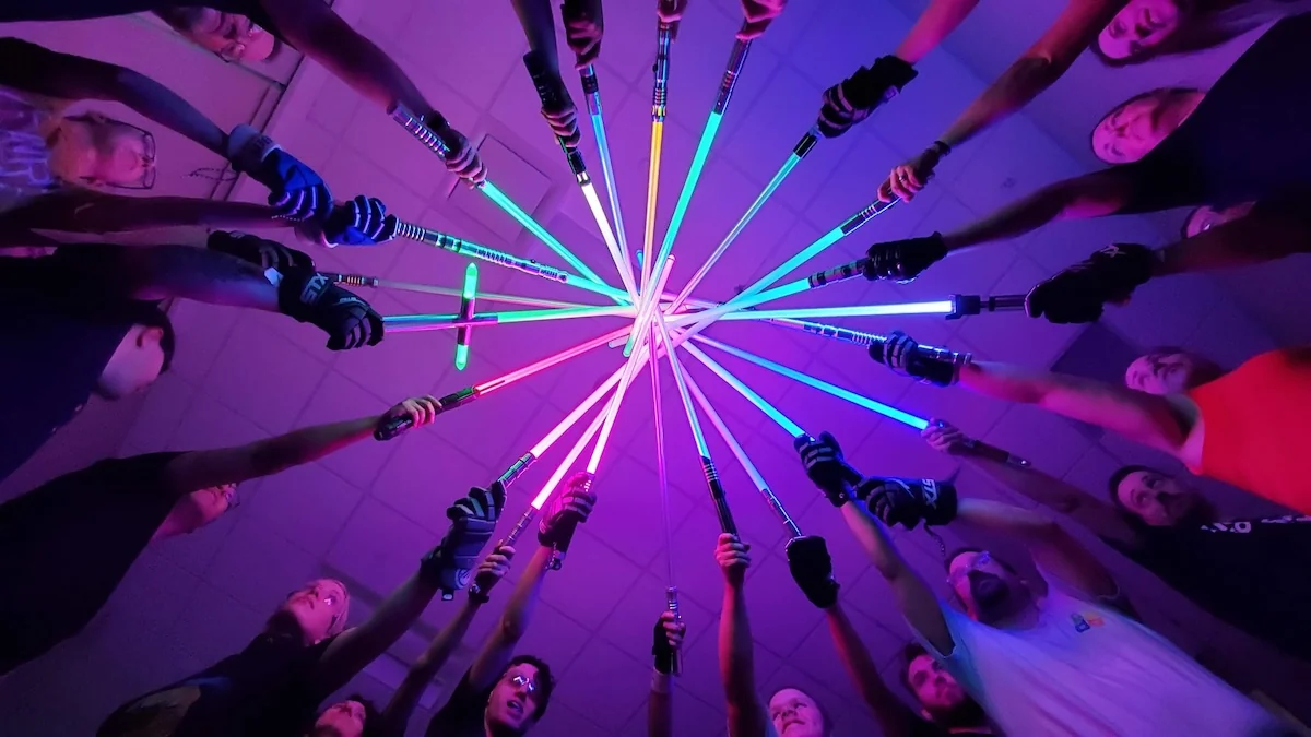 Academy participants form a circle, bringing their colorful illuminated sabers together overhead.